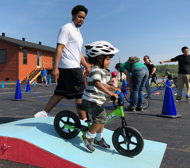 Father next to son on a balance bike at a Buddy Pegs class